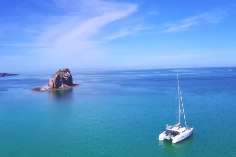 Arias Song Yacht Photos Pics Lagoon 400 S2 catamaran sailing near a small island in clear blue waters, 2016 model.