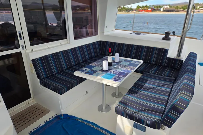 Arias Song Yacht Photos Pics Outdoor seating area on 2016 Lagoon 400 S2 catamaran with striped cushions and table setting.