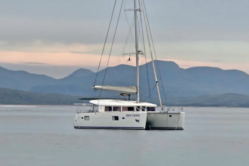Arias Song Yacht Photos Pics 2016 Lagoon 400 S2 catamaran sailing on calm waters with mountain backdrop.