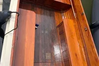 1926 custom motorboat with polished wooden interior, docked on calm water.