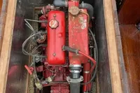 Red engine of a 1926 custom motorboat, displayed in a wooden compartment.
