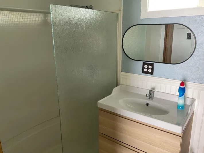  Yacht Photos Pics Modern bathroom with glass shower, wooden vanity, and oval mirror in a 1980 Custom Boathouse.