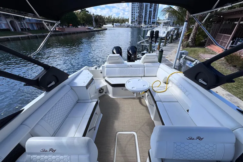  Yacht Photos Pics 2024 Sea Ray SDX 290 Outboard boat interior with white seating, docked by a scenic waterfront.