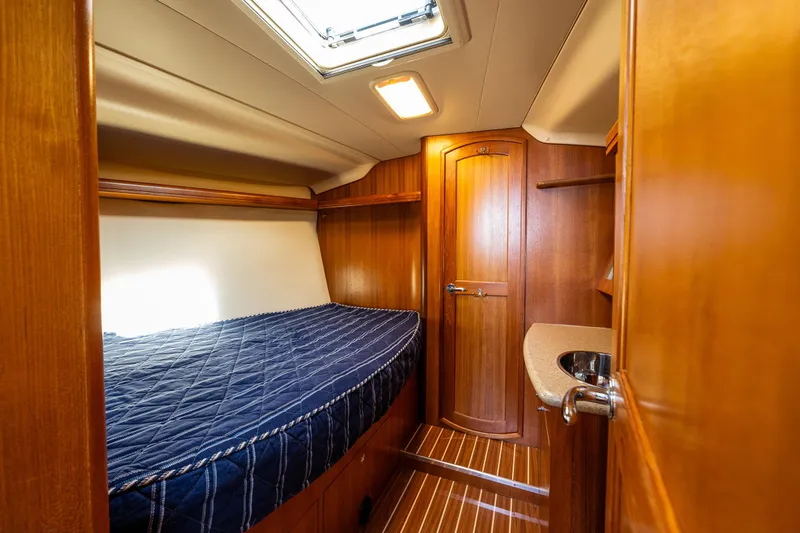 Selkie Yacht Photos Pics Cozy cabin interior of 2007 Hunter 41 Deck Salon with wooden finish and blue bedding.