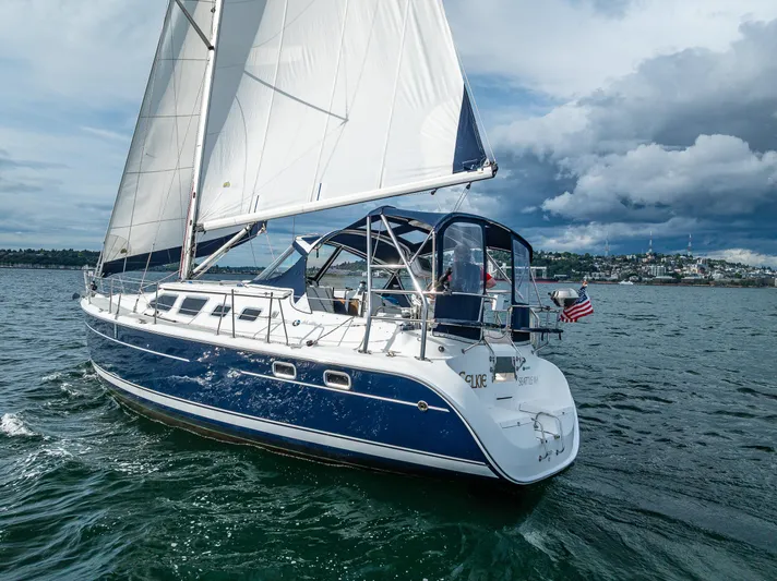 Selkie Yacht Photos Pics 2007 Hunter 41 Deck Salon sailboat cruising on a scenic waterway under cloudy skies.