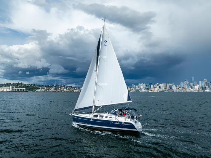Selkie Yacht Photos Pics Sailboat Hunter 41 Deck Salon 2007 cruising near city skyline under dramatic clouds.