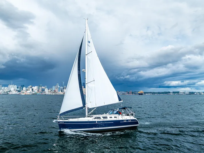 Selkie Yacht Photos Pics Sailing yacht Hunter 41 Deck Salon, 2007, cruising near city skyline under cloudy skies.