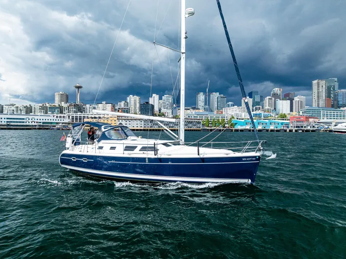Selkie Yacht Photos Pics 2007 Hunter 41 Deck Salon sailboat cruising near urban skyline under cloudy skies.