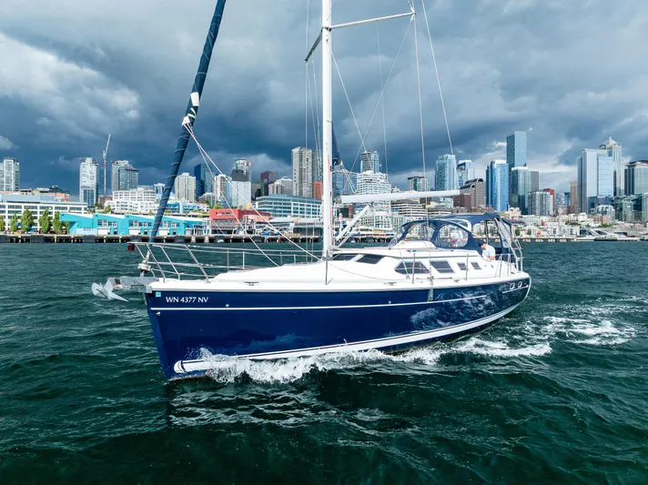 Selkie Yacht Photos Pics 2007 Hunter 41 Deck Salon sailing near a city skyline under cloudy skies.