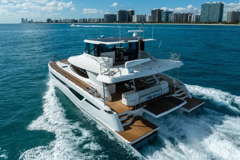 Bikini Bottom Yacht Photos Pics Luxurious 2023 Granocean 57 yacht cruising near a city skyline on a sunny day.