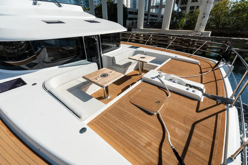 Bikini Bottom Yacht Photos Pics Luxurious 2023 Granocean 57 yacht deck with seating and tables, docked under a bridge.