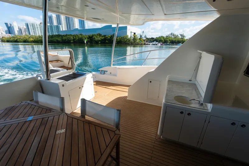 Bikini Bottom Yacht Photos Pics Luxurious Granocean 57 yacht deck with city skyline, featuring outdoor kitchen and seating, 2023 model.
