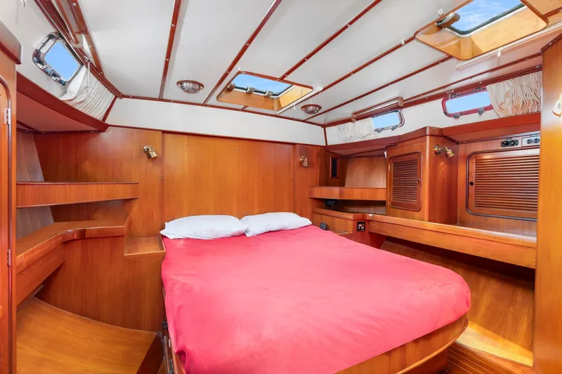 Mandate Yacht Photos Pics Luxurious 1996 Tayana 58 yacht cabin with wooden interior and red bedding.