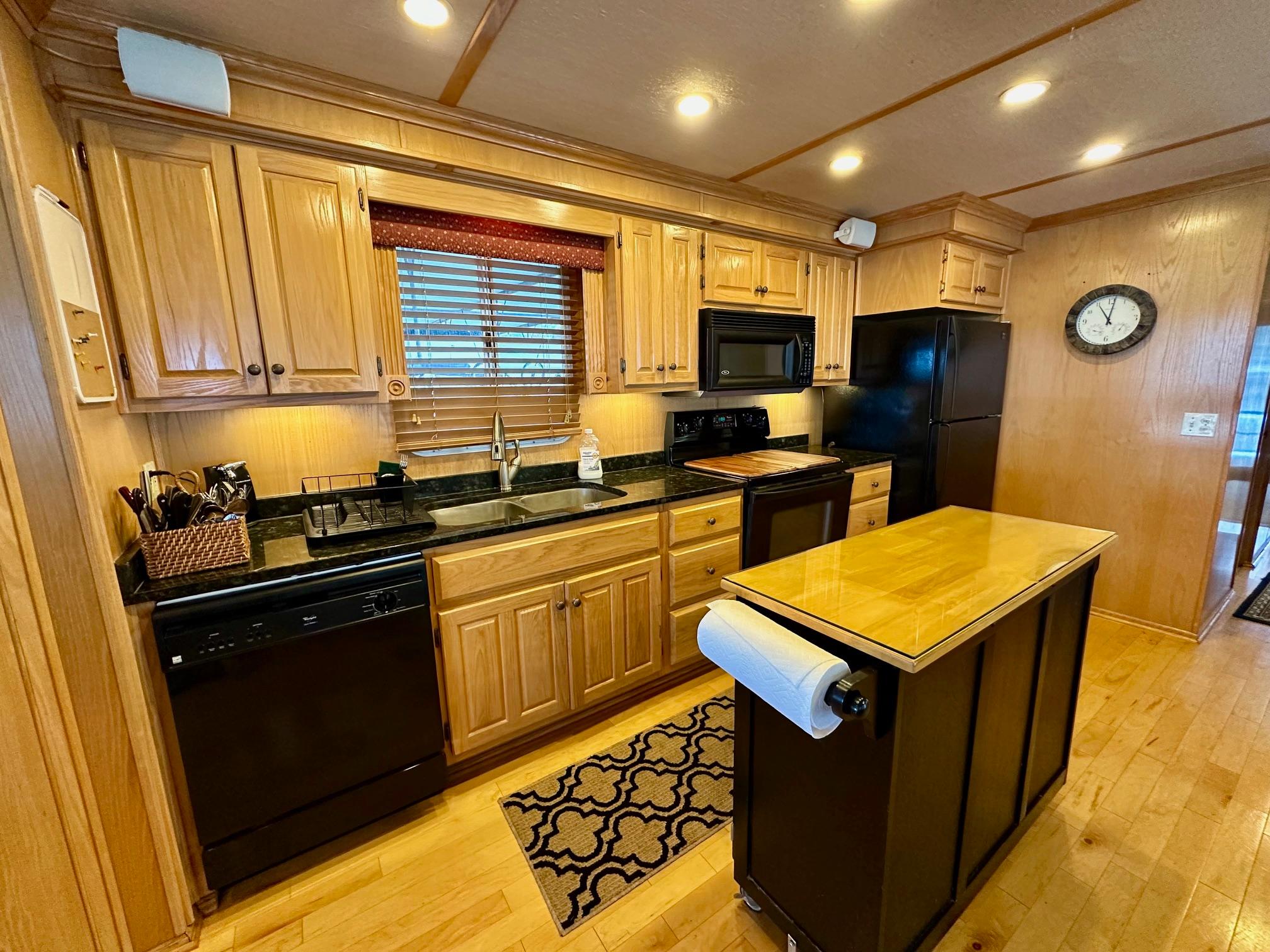 Modern kitchen in 2004 Lakeview 16x68 houseboat with wooden cabinets and black appliances.