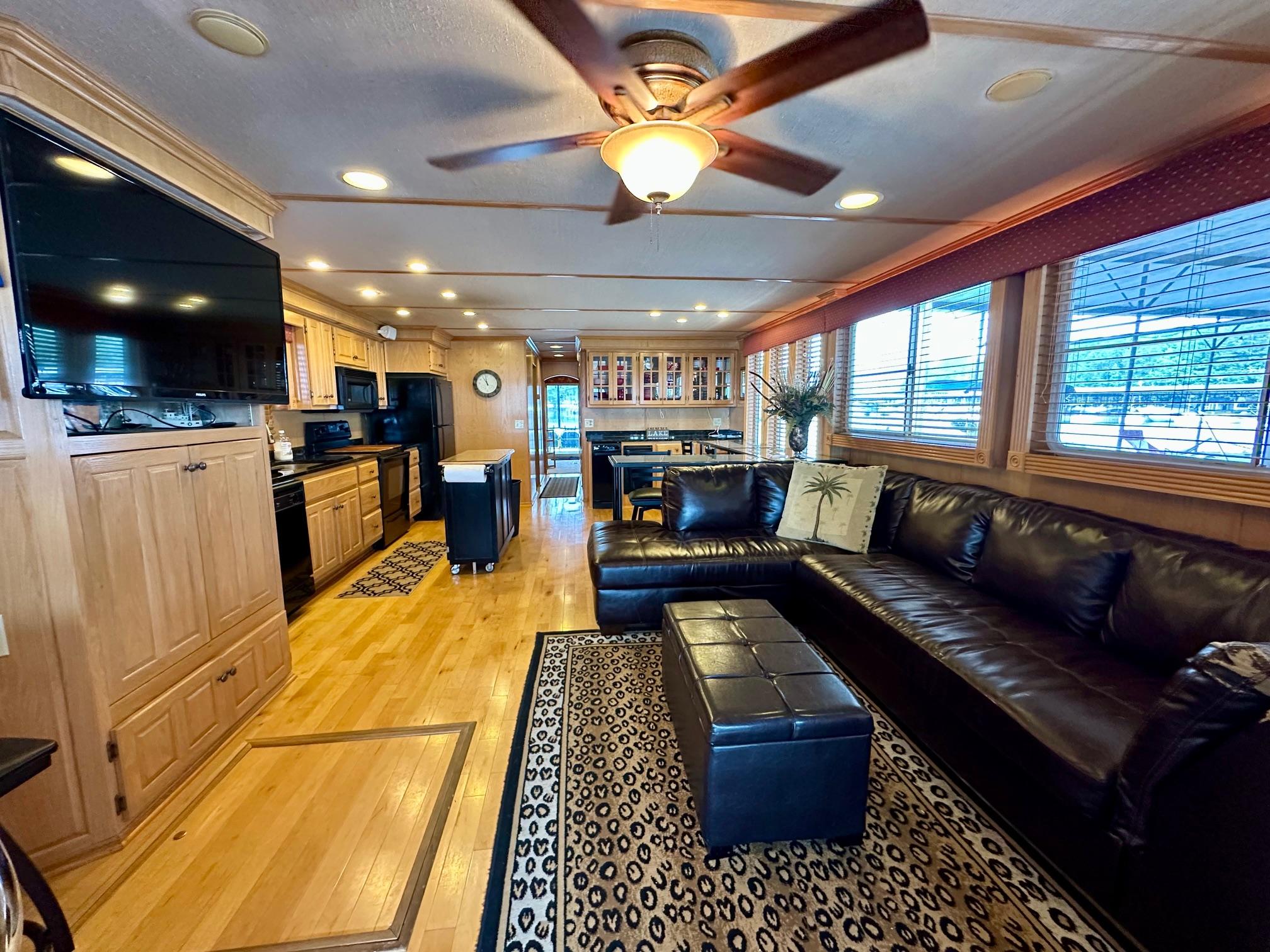 Luxurious 2004 Lakeview 16x68 houseboat interior with leather seating, modern kitchen, and ceiling fan.
