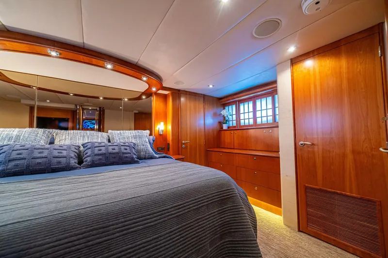 Prime Time Yacht Photos Pics Luxurious bedroom interior of 2002 Queenship 98 Yachtfish, featuring elegant wood finishes and cozy bedding.