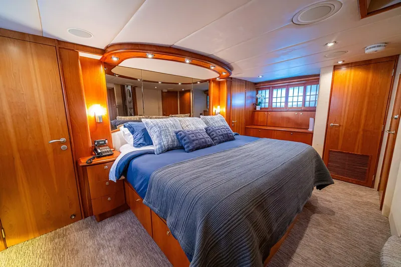 Prime Time Yacht Photos Pics Luxurious bedroom on 2002 Queenship 98 Yachtfish, featuring elegant wood paneling and plush bedding.