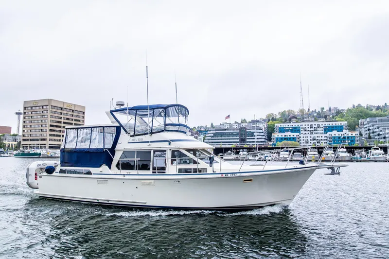 Blue Fish Yacht Photos Pics 1988 Tollycraft 44CPMY yacht cruising in urban marina with cityscape backdrop.