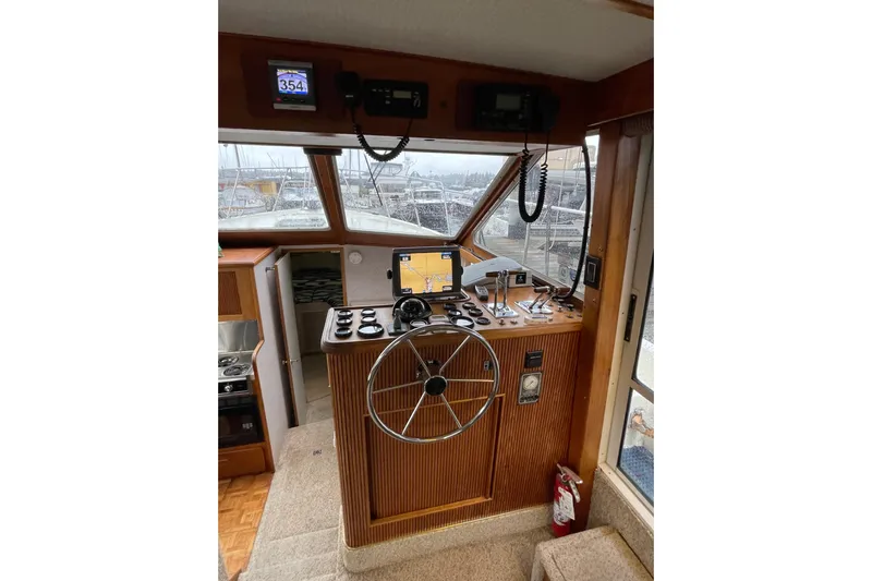 Blue Fish Yacht Photos Pics 1988 Tollycraft 44CPMY helm with steering wheel, navigation equipment, and wood paneling.