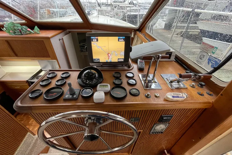 Blue Fish Yacht Photos Pics 1988 Tollycraft 44CPMY helm with navigation instruments and steering wheel in a rainy marina setting.