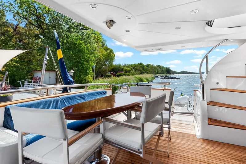  Yacht Photos Pics Luxury yacht deck with dining area, overlooking serene waters and lush greenery. Horizon Elegance 80, 2000.