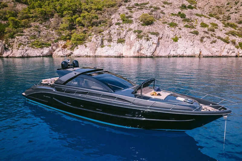 Who Cares Yacht Photos Pics Luxury 2006 Riva 68 Ego yacht on serene blue water near rocky coastline.