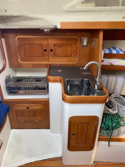4817rf Yacht Photos Pics Compact kitchen area in a 2013 Tartan 101 sailboat with stove, sink, and storage.