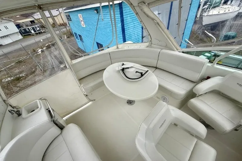  Yacht Photos Pics 2004 Carver 450 Voyager Pilothouse interior with white seating and table, docked near blue building.