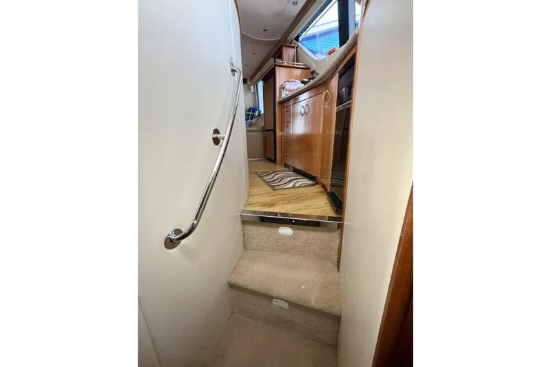  Yacht Photos Pics Interior stairs of 2004 Carver 450 Voyager Pilothouse, featuring wooden cabinetry and carpeted steps.