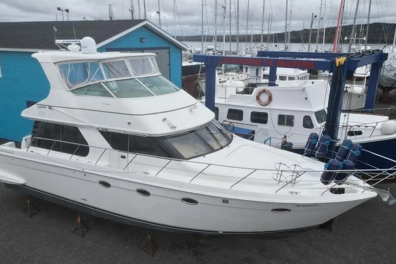  Yacht Photos Pics 2004 Carver 450 Voyager Pilothouse yacht docked at a marina with blue building.