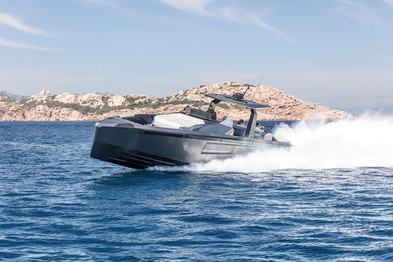  Yacht Photos Pics 2026 Maori Yacht cruising swiftly on blue ocean near rocky coastline.