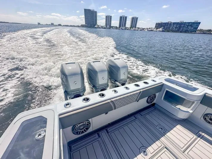 Fortuna Yacht Photos Pics 2021 SeaVee 370z boat with triple engines cruising on open water, city skyline in background.