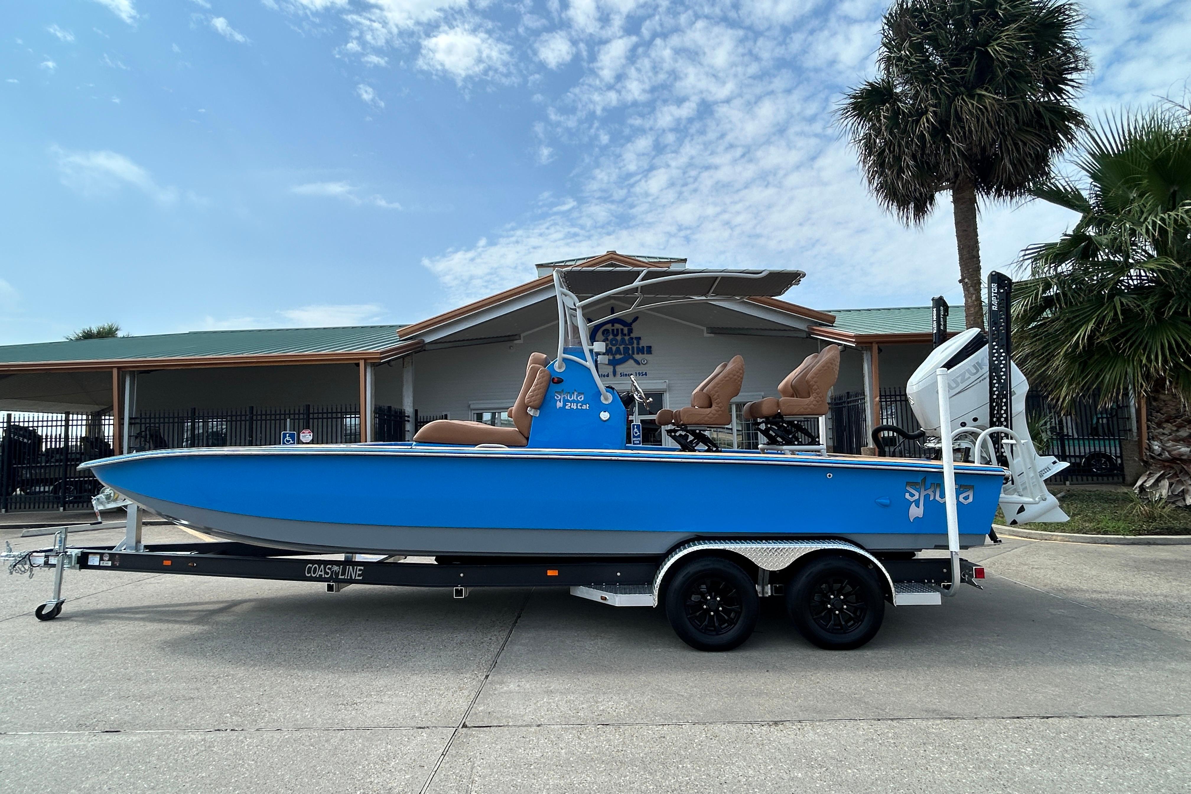 2026 Skuta 24 Skuta Cat boat on trailer, blue hull, parked outdoors.