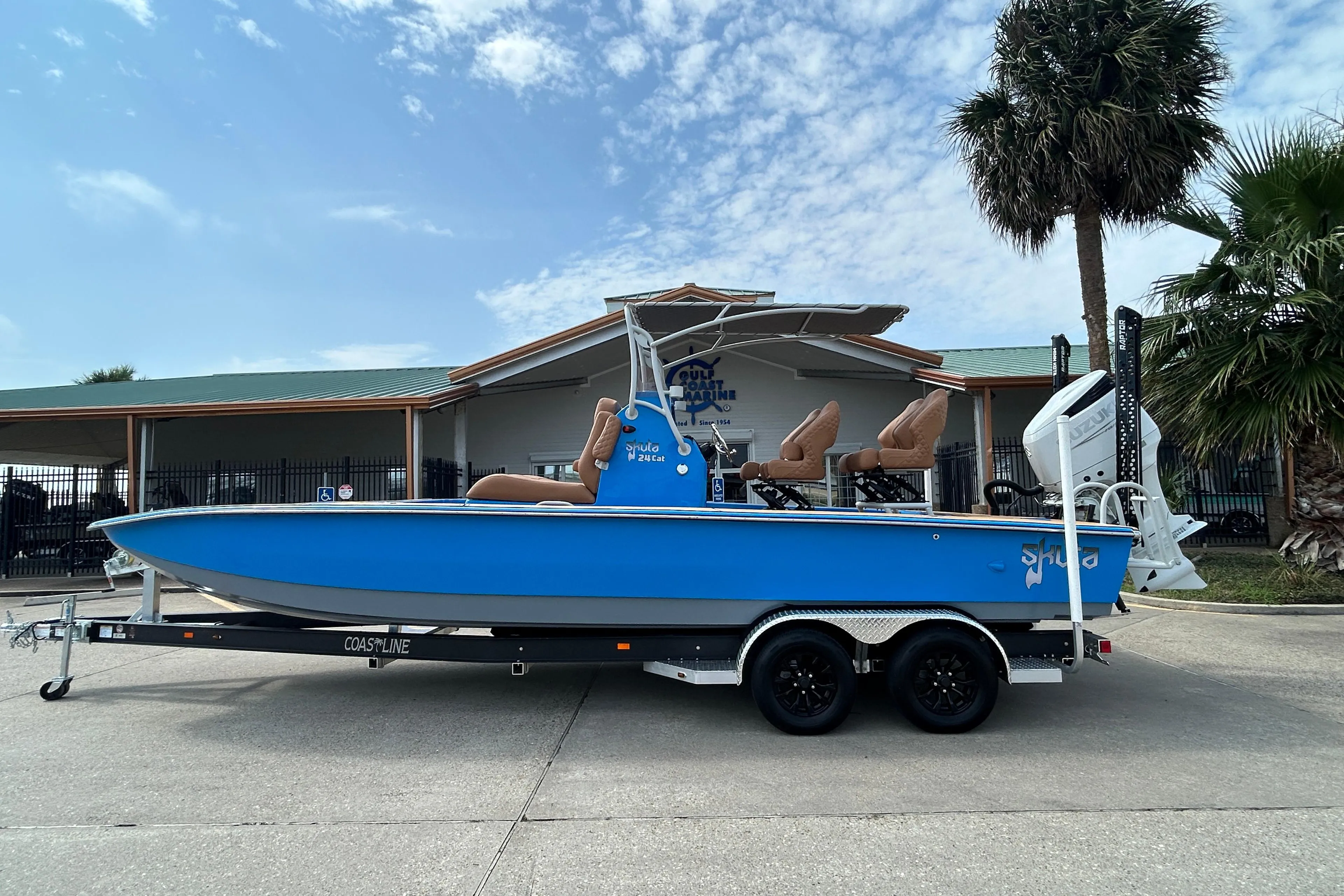2026 Skuta 24 Skuta Cat boat on trailer, blue hull, parked outdoors.