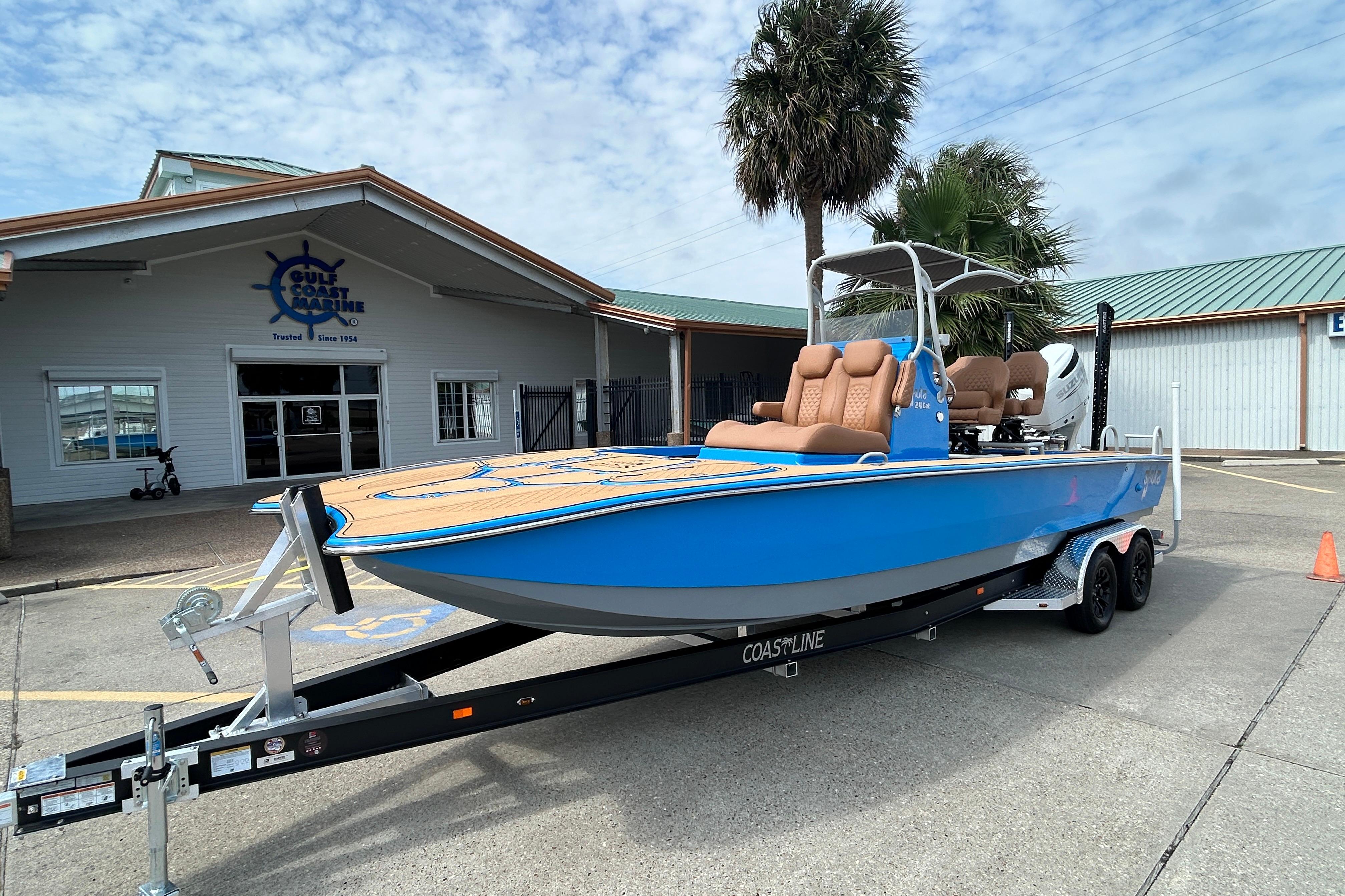2026 Skuta 24 Skuta Cat boat on trailer outside Gulf Coast Marine building.