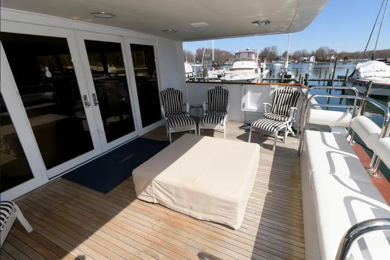 Liquidity Yacht Photos Pics Spacious deck of 1984 Broward Raised Pilothouse yacht with striped chairs and marina view.