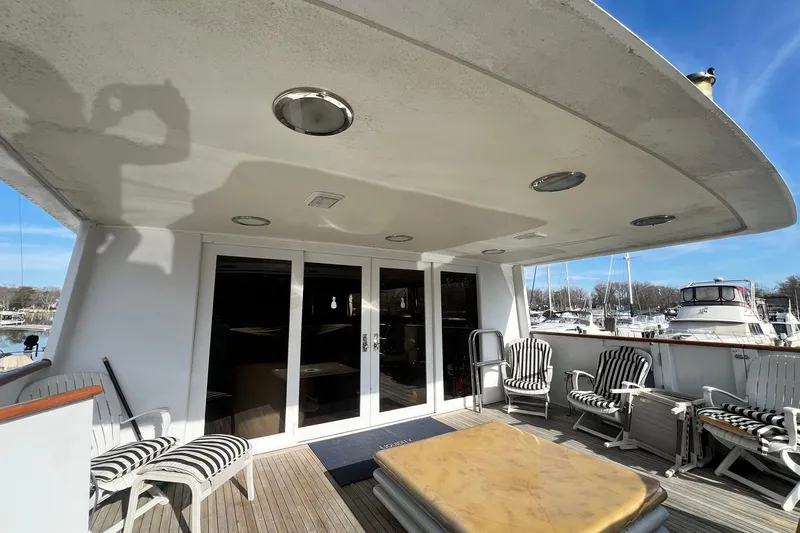 Liquidity Yacht Photos Pics 1984 Broward Raised Pilothouse yacht deck with striped chairs and marina view.