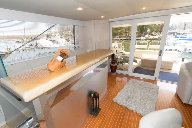 Liquidity Yacht Photos Pics Luxurious 1984 Broward Raised Pilothouse yacht interior with bar, plush seating, and marina view.