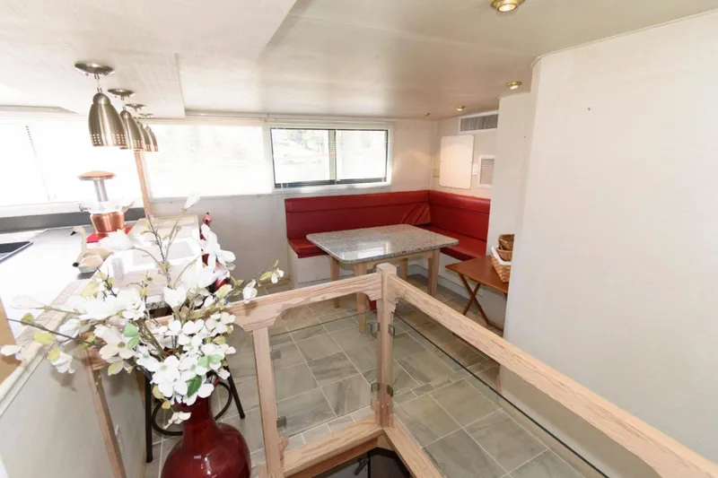 Liquidity Yacht Photos Pics Interior of 1984 Broward Raised Pilothouse with red seating, dining table, and floral decor.