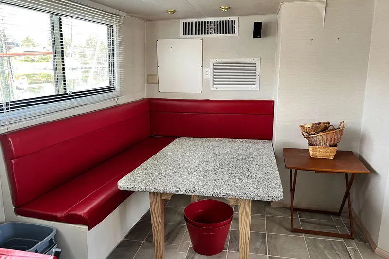 Liquidity Yacht Photos Pics Cozy dining area in 1984 Broward Raised Pilothouse with red seating and granite table.