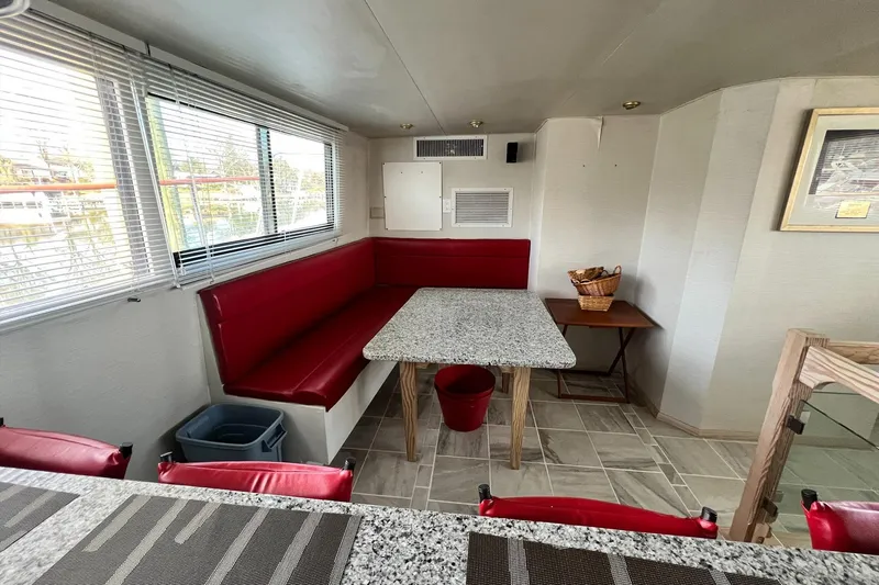 Liquidity Yacht Photos Pics Interior of 1984 Broward Raised Pilothouse with red seating and granite table.