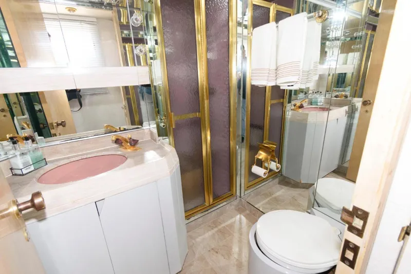 Liquidity Yacht Photos Pics Luxurious 1984 Broward Raised Pilothouse yacht bathroom with gold accents and pink sink.