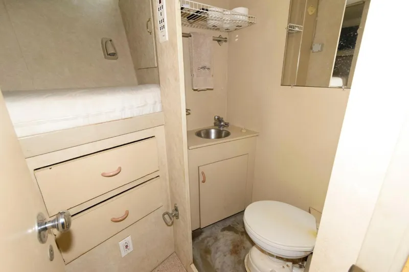 Liquidity Yacht Photos Pics Compact bathroom in 1984 Broward Raised Pilothouse yacht with sink, toilet, and storage.