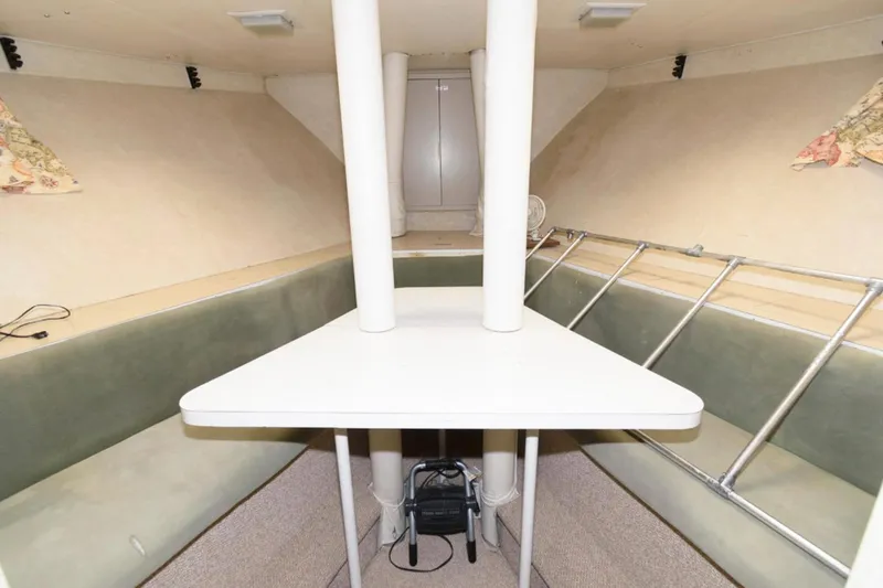 Liquidity Yacht Photos Pics 1984 Broward Raised Pilothouse interior with table, seating, and ladder in a cozy cabin space.