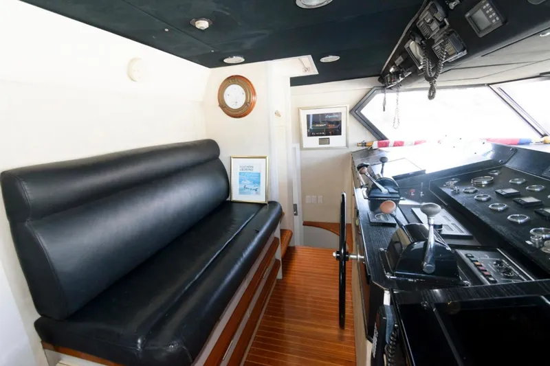 Liquidity Yacht Photos Pics Interior of 1984 Broward Raised Pilothouse yacht with black seating and control panel.