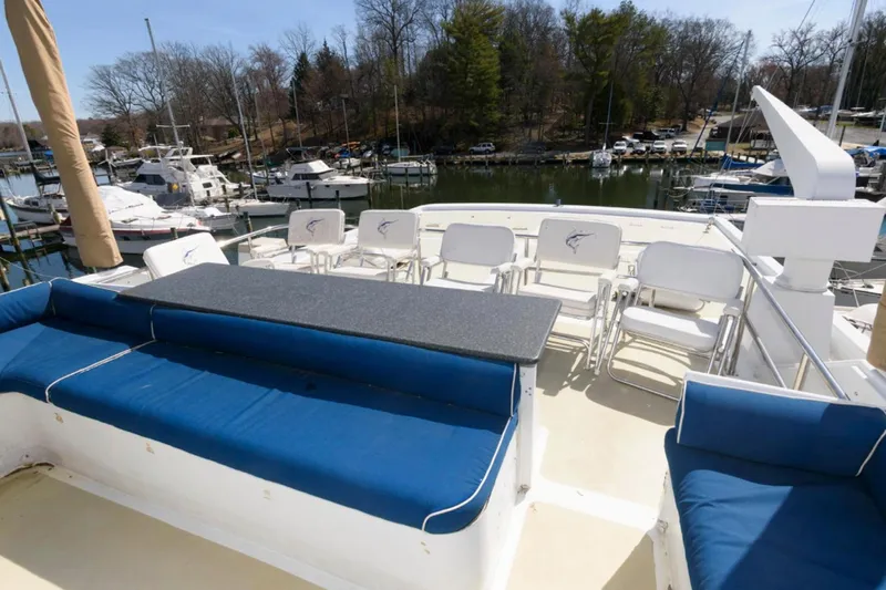 Liquidity Yacht Photos Pics 1984 Broward Raised Pilothouse yacht deck with blue seating and marina view.