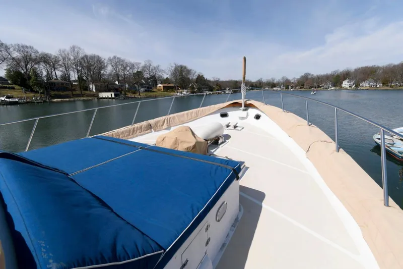Liquidity Yacht Photos Pics 1984 Broward Raised Pilothouse yacht on a serene river with clear skies.