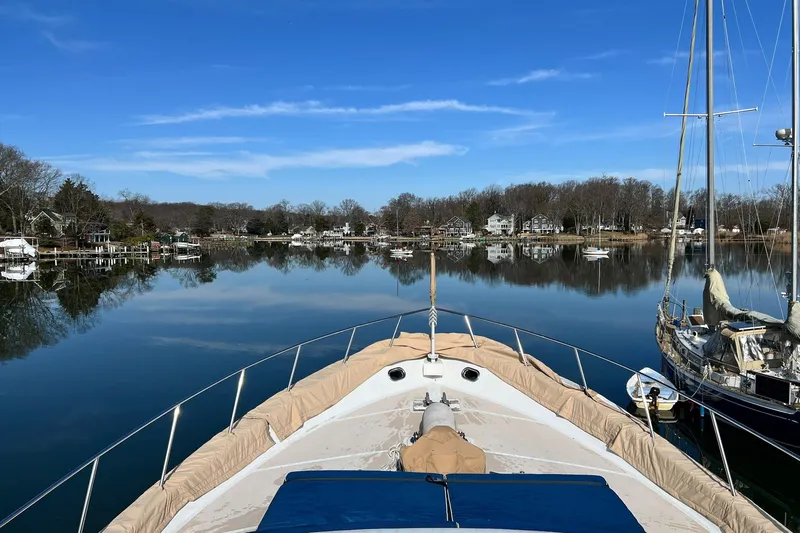 Liquidity Yacht Photos Pics 1984 Broward Raised Pilothouse yacht on serene lake with clear blue sky.