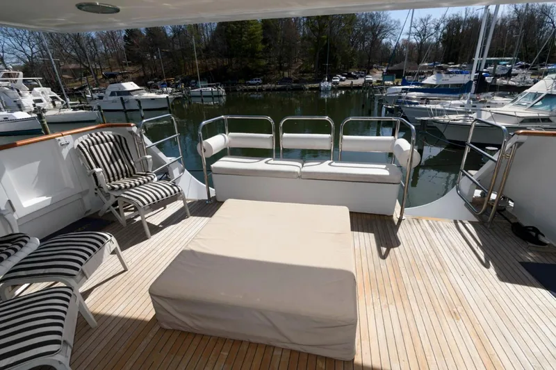 Liquidity Yacht Photos Pics Luxury yacht deck with striped chairs, Broward Raised Pilothouse, 1984, docked at marina.