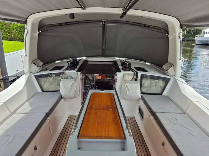 Wanderer Yacht Photos Pics 2019 Beneteau Oceanis 41.1 yacht cockpit with seating and wooden table, docked by the water.